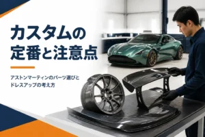 作業台のカーボン部品とホイールの奥に停まるスポーツクーペ
